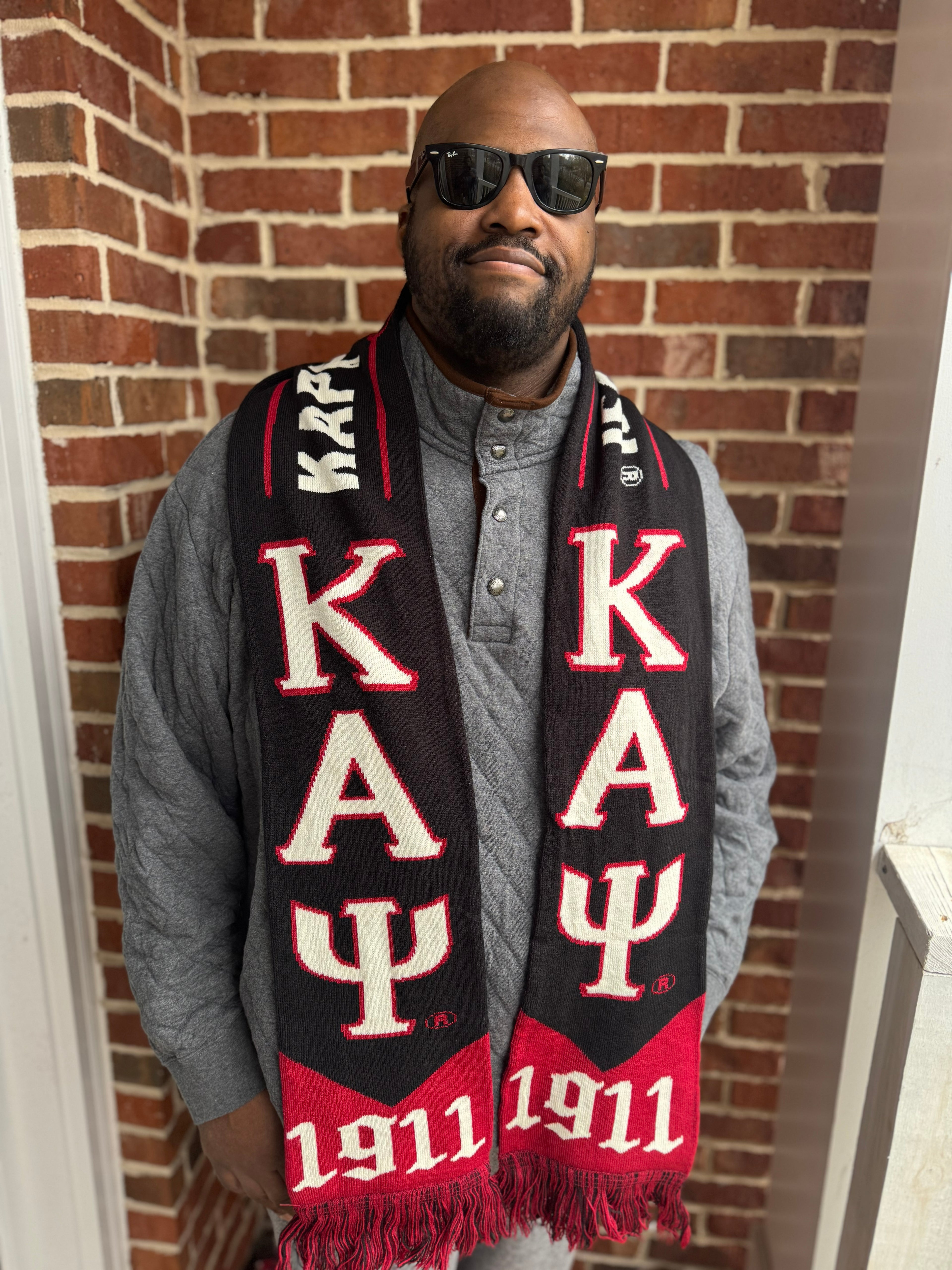 Man wearing a Kappa Alpha Psi scarf in front of a brick wall
