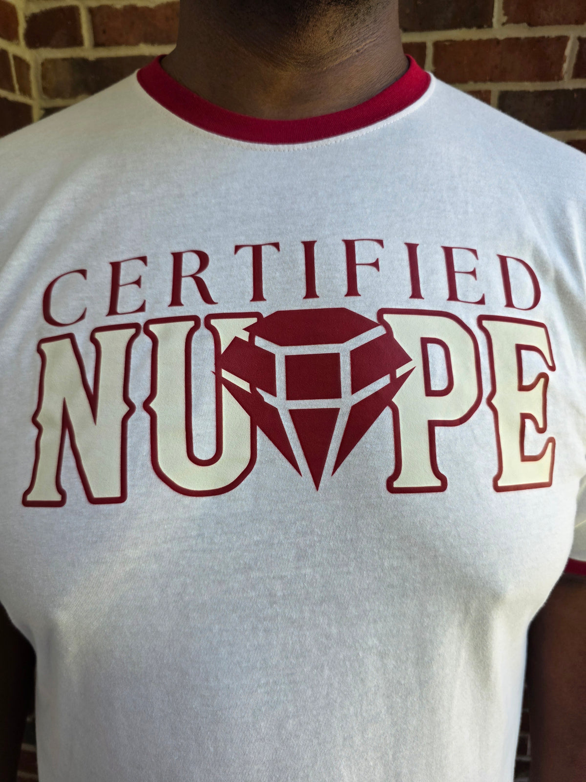 Close-up of Kappa Alpha Psi Certified Nupe graphic print on cream cotton ringer tee shirt
