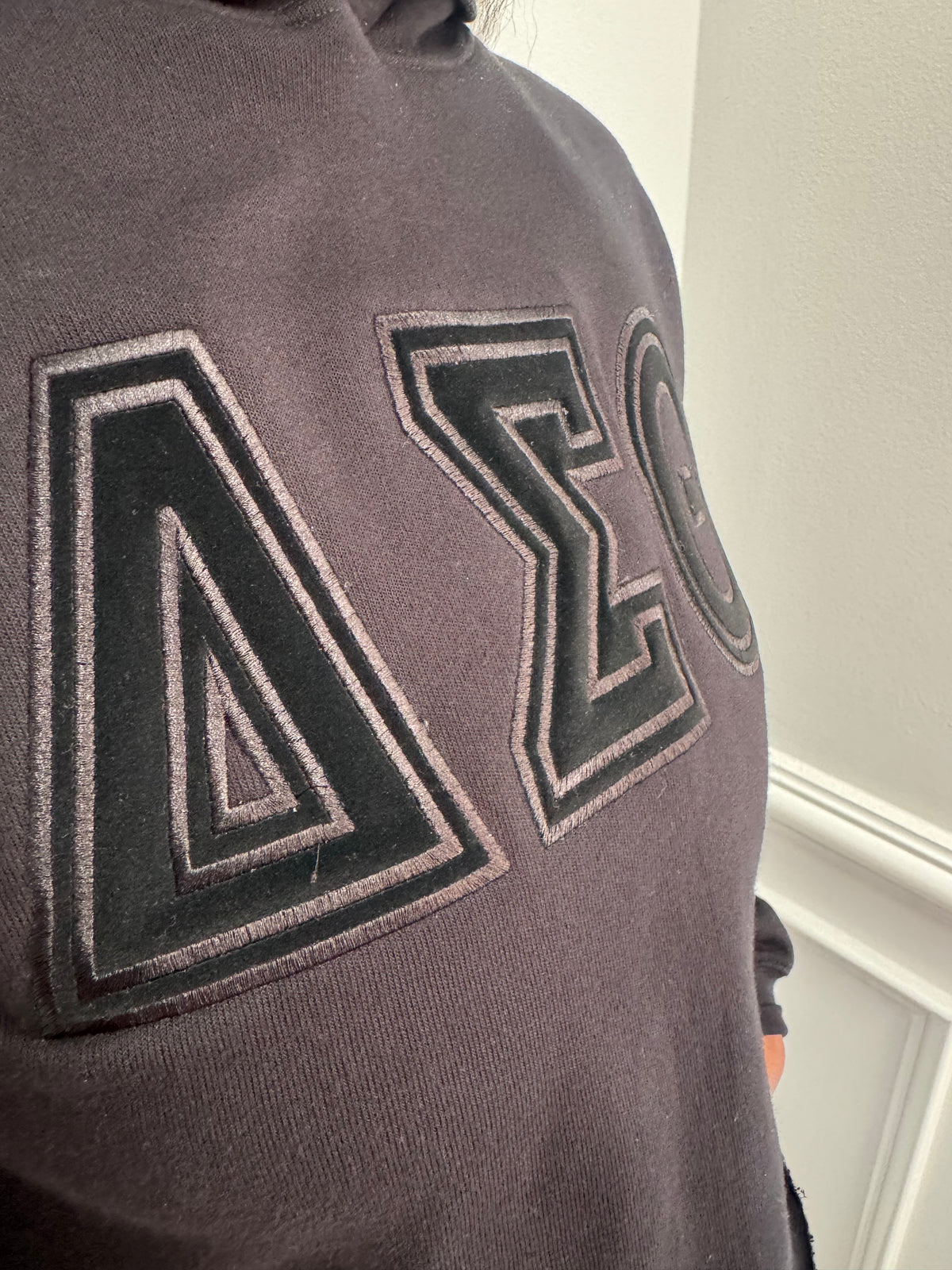 Delta Sigma Theta black-on-black cropped hoodie with embroidered Greek letters front view.