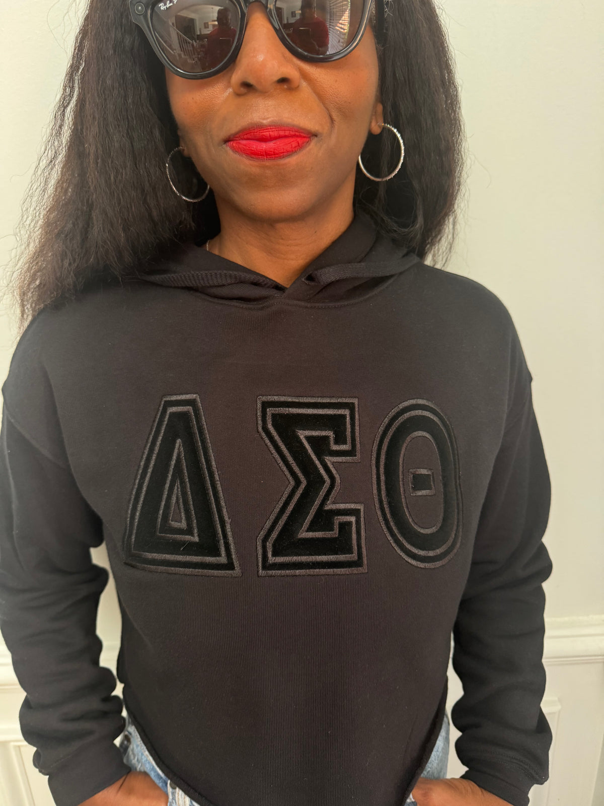 Close-up view of raised black satin stitch embroidery on black fleece crop hoodie. Delta Sigma Theta black-on-black cropped hoodie