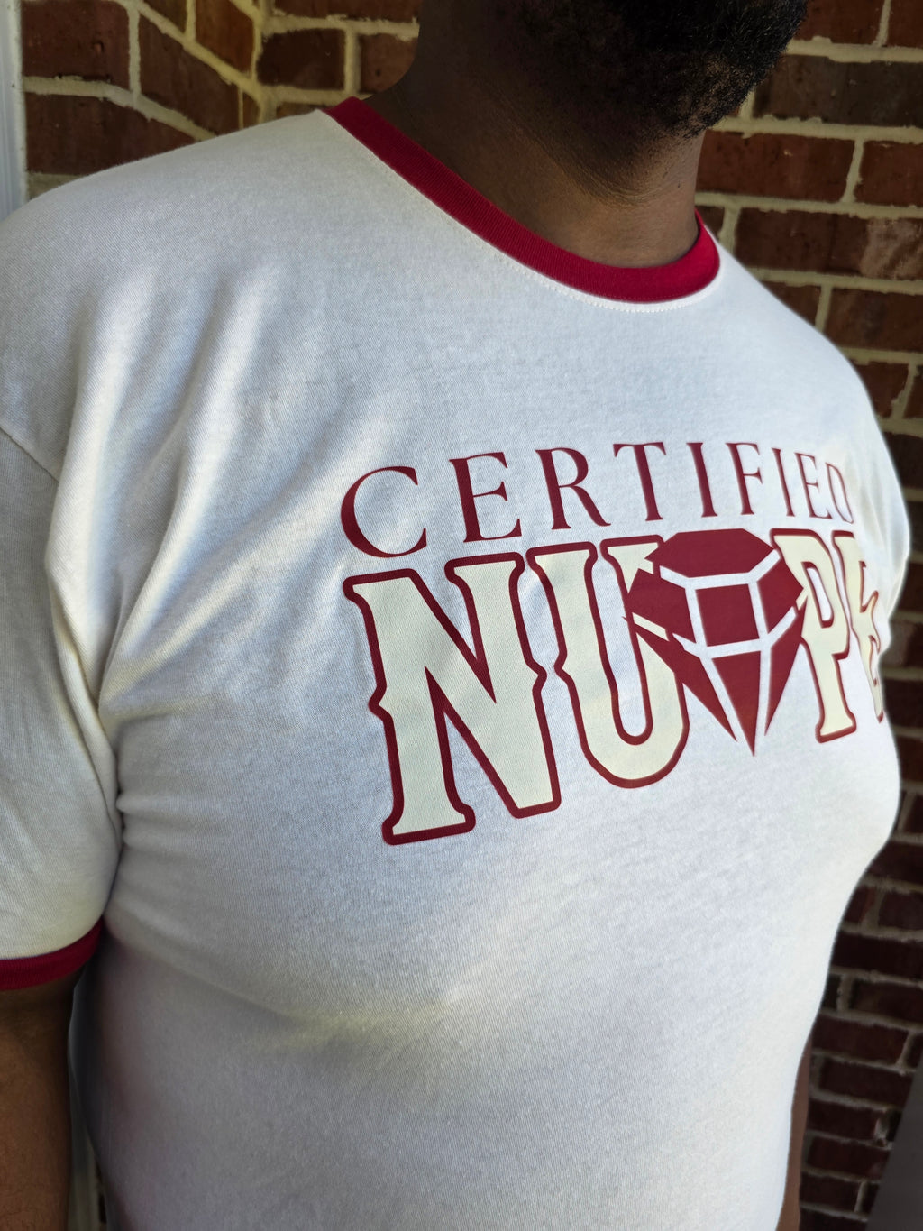 Close-up of Certified Nupe graphic print on cream cotton ringer tee shirt