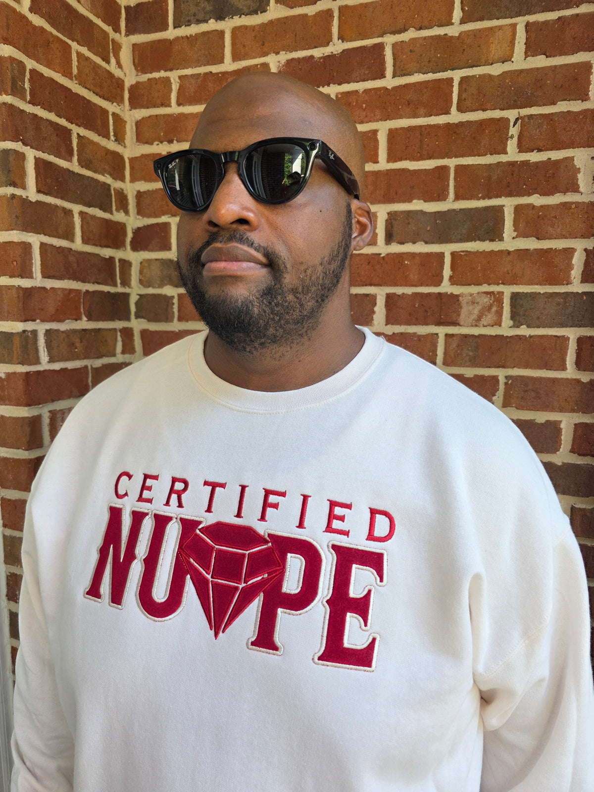 Detailed view of high-density satin stitch Certified Nupe embroidery on cream fleece crewneck